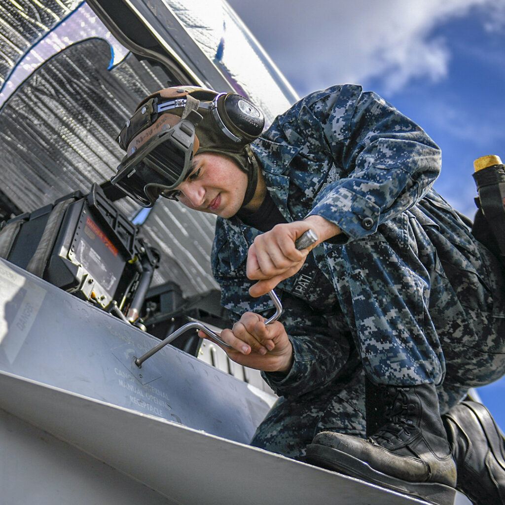 180501-N-NK192-1049 PEARL HARBOR, Hawaii (May 1, 2018) Airman Vincent Scalpati tightens a panel on an EA-18G Growler, assigned to the Cougars of Electronic Attack Squadron (VAQ) 139, on the flight deck of the aircraft carrier USS Theodore Roosevelt (CVN 71). Theodore Roosevelt is currently deployed in the Pacific Ocean. (U.S. Navy photo by Mass Communication Specialist Seaman Michael A. Colemanberry/Released)