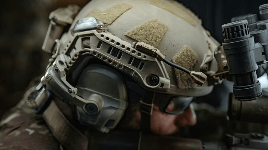 A tan tactical helmet with adjustable straps and accessory mounts.